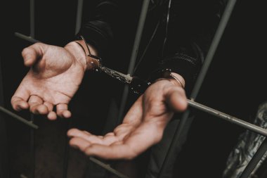 Adam bir polis istasyonunda kelepçe arkasında barlarda.