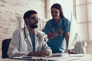 Genç erkek doktor ofiste bilgisayarla çalışıyor. Hemşire Yakın Duruyor. Erkek Labaratuar Araştırmacısı, Kişisel Bilgisayarında Grafiklerle Çalışıyor. Tıp Konsepti. Sağlık Konsepti.