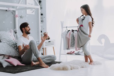 Baba Yardım Kız Yatak Odasında Bir Elbise Seçimi. Pretty Little Happy Girl Dolap Giysiler arasında Sneaking. Hayal Gücü veya Yaratıcılık Kavramı için Bir Clothesline Asılı Giyim Giyinmek.