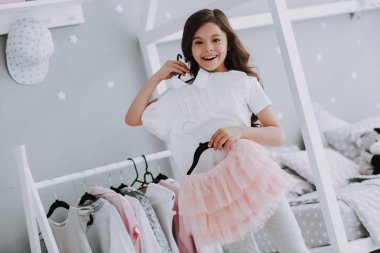 Küçük Sevimli Kız Yatak Odasında Bir Elbise Seçimi. Pretty Little Happy Girl Dolap Giysiler arasında Sneaking. Hayal Gücü veya Yaratıcılık Kavramı için Bir Clothesline Asılı Giyim Giyinmek.