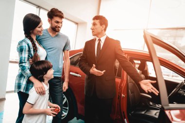 Mutlu genç aile galeride yeni bir araba tercih ediyor. Diyalog satıcı ile. Neşeli müşteri. Otomatik tanıtımı. Karar verin. Bir anlaşma sona erdi. İyi bir teklif. Alıcı ve satıcı. İş Ticaret.