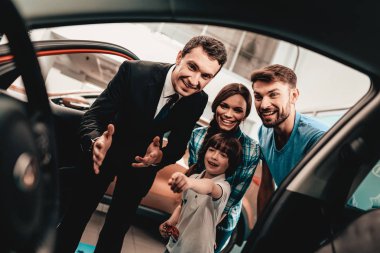 Mutlu genç aile galeride yeni bir otomatik tercih ediyor. Diyalog satıcı ile. Neşeli müşteri. Arabanın içine bak. Karar verin. Bir anlaşma sona erdi. İyi bir teklif. Alıcı ve satıcı. İş Ticaret.