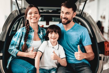 Aile yeni bir arabanın bagajında oturuyor. Çok iyi. Bir galeride satın alma. Otomobil Salon. Mutlu birlikte. Başarılı bir seçim. İyi bir ruh hali. Büyük ticaret. Otomatik tanıtımı. Bir karar.