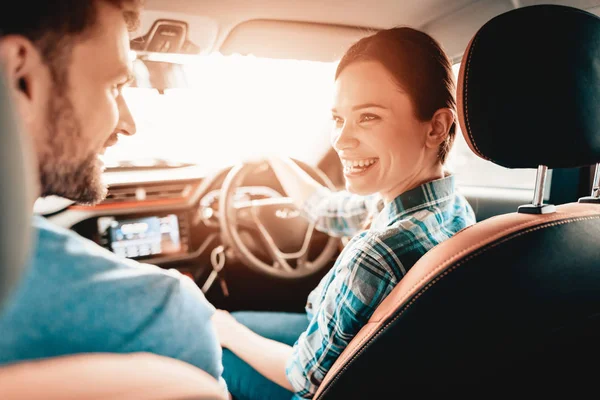 微笑的情侣坐在一个新车的跛脚年轻的家庭 汽车沙龙 开朗的司机 成功购买 好心情 伟大的贸易 阳光明媚的挡风玻璃 看着对方 — 图库照片