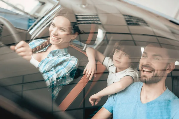 A Woman Is Sitting At The Wheel Of A New Vehicle. Young Family. Car Buying In A Showroom. Automobile Salon. Cheerful Driver. Happy Together. Successful Buying. Good Mood. Great Trade.