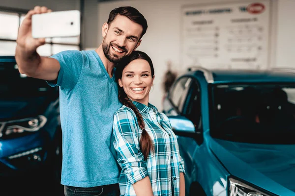 男と女は 彼らの新しい車の近くの Selfie を行います 自動車のサロン 決定を下します 幸せな一緒に 良い提供しています 幸せな一緒に 成功を購入します — ストック写真