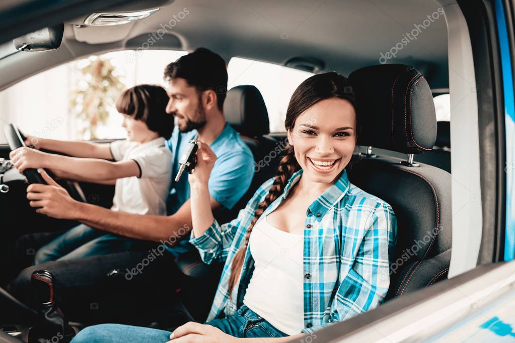 Man With Son Are Sitting At The Wheel Of New Vehicle. Smiling Family. Car Buying In A Showroom. Automobile Salon. Cheerful Driver. Happy Together. Successful Driving. Good Mood. Great Trade.