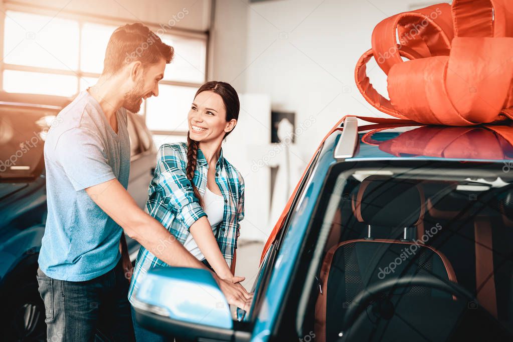 A Guy Shows A New Car To Girlfriend. Present Concept. Staring At Each Other. Automobile Salon. Make A Decision. Door Open. End Of A Deal. Good Offer. Happy Together. Successful Buying.
