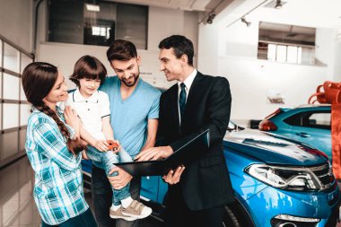 Mutlu genç aile galeride yeni bir araba tercih ediyor. Diyalog satıcı ile. Neşeli müşteri. Otomobil Salon. Karar verin. Tablet hakkında bilgi. İyi bir teklif. Alıcı ve satıcı. İş Ticaret.