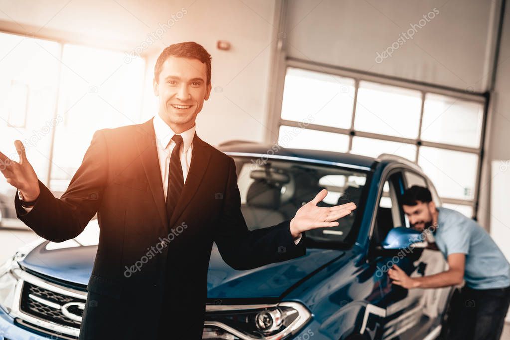 Car Dealer Camera Posing With A Buyer On Background. Cheerful Customer. Automobile Salon. Make A Decision. End Of A Deal. Good Offer. New Buying. Business Trade. Confident Seller. Arms Crossed.