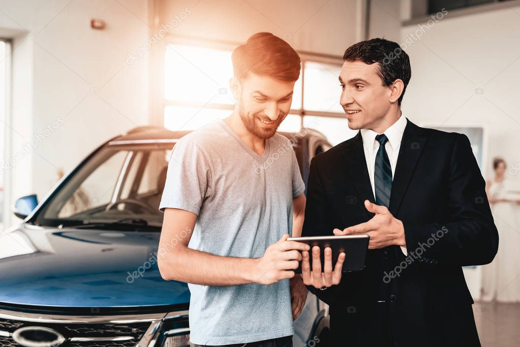 The Man And The Seller Talk About Cars In Showroom. Dialogue With Dealer. Cheerful Customer. Automobile Salon. Information On Tablet. End Of A Deal. Good Offer. Buyer And Dealer. Business Trade.