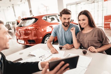 Mutlu genç aile galeride yeni bir araba tercih ediyor. Diyalog satıcı ile. Neşeli müşteri. Otomobil Salon. Karar verin. Bir fincan kahve. Bir anlaşma sona erdi. İyi bir teklif. Tablet hakkında bilgi.