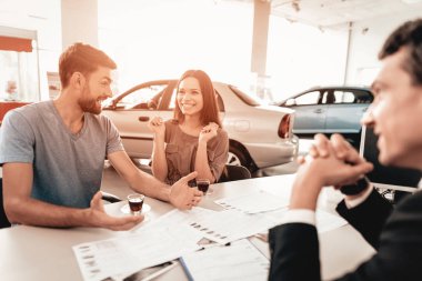 Mutlu genç aile galeride yeni bir araba tercih ediyor. Diyalog satıcı ile. Neşeli müşteri. Otomobil Salon. Karar verin. Bir fincan kahve. Bir anlaşma sona erdi. İyi bir teklif. Alıcı ve satıcı.