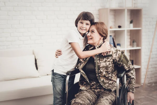 Woman Veteran In Wheelchair Homecoming Concept. Family Meeting. Leaving From War. Embrace With Child. Camouflage Uniform. Son Hanging. Feelings Showing. Patriotic Comeback. Paralyzed Soldier.