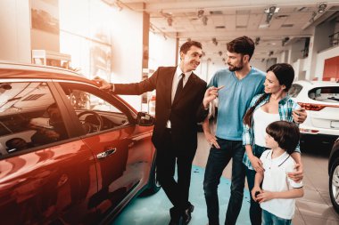 Mutlu genç aile galeride yeni bir araba tercih ediyor. Diyalog satıcı ile. Neşeli müşteri. Otomatik tanıtımı. Karar verin. Bir anlaşma sona erdi. İyi bir teklif. Alıcı ve satıcı. İş Ticaret.