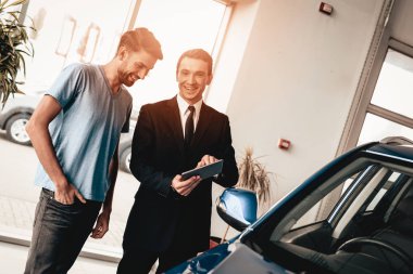 Adam ve satıcı showroom arabalar hakkında konuş. Diyalog satıcı ile. Neşeli müşteri. Otomobil Salon. Tablet hakkında bilgi. Bir anlaşma sona erdi. İyi bir teklif. Alıcı ve satıcı. İş Ticaret.