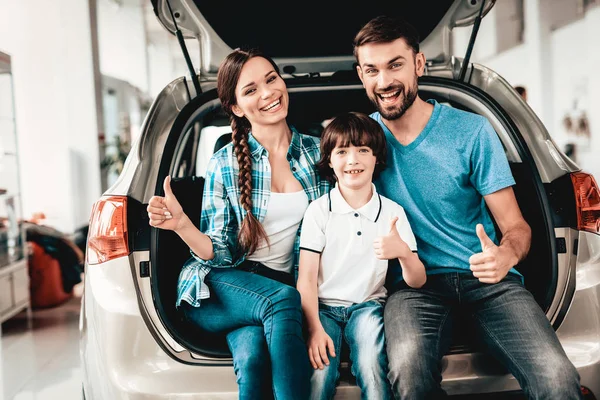 Family Are Sitting In The Trunk Of A New Car. Thumbs Up. Buying In A Showroom. Automobile Salon. Happy Together. Successful Choice. Good Mood. Great Trade. Auto Rewiew. Make A Decision.