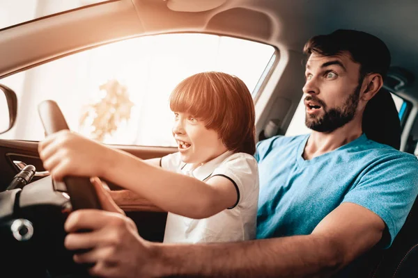 Man With Kid Are Sitting At The Wheel Of New Vehicle. Smiling Family. Car Buying In A Showroom. Automobile Salon. Cheerful Driver. Happy Together. Father And Son. Good Mood. Great Trade.