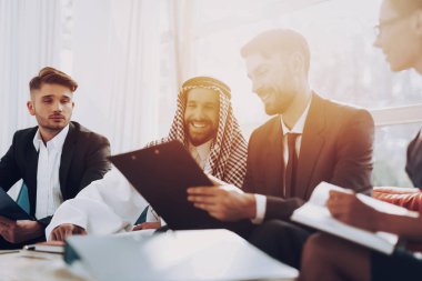 Arap işadamı tartışma toplantı ortakları ile. Para yatırım. Kağıt belgeleri. Yöneticileri ile konuşuyor. Ortaklık Anlaşması. Disdash ve Keffiyeh giyiyor. Laptop ile çalışmak.