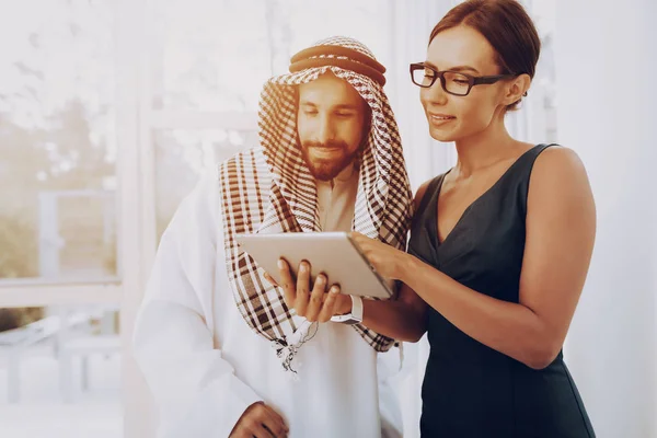 Girl Talking With Arab About Business Partnership. Money Investment. Paper Documents. Business Strategy. Working With Tablet. Disdash And Keffiyeh Wearing. Professional Discussion With Manager.