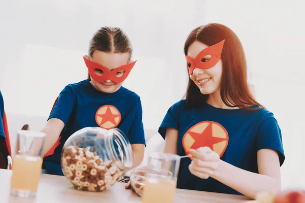 Young Family In Superhero Suits. Dinner Concept. Masks And Raincoats. Bright Room. Resting Together. Juice And Cereals. Get Ready. Healthy Lifestyle. Kids With A Parents. Active Leisure.