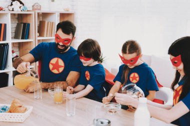 Süper kahraman takım elbiseli Genç aile. Akşam yemeği kavramı. Maskeleri ve yağmurluklar. Parlak oda. Birlikte dinleniyor. Suyu ve tahıllar. Hazır olun. Sağlıklı bir yaşam tarzı. Bir anne ile çocuk. Etkin boş.