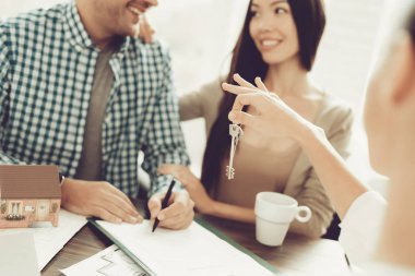 Emlakçı ofisinde gülümseyen kadın ve genç erkek. Ahşap masa planı. Emlak kavramları. Genç bir çift. Yeni ev satın alma. Office ailesi. Kiralık Ajan kavramı. Mutlu bir aile.