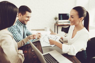 Emlakçı ofisinde gülümseyen kadın ve genç erkek. Ahşap masa planı. Emlak kavramları. Genç bir çift. Yeni ev satın alma. Office ailesi. Kiralık Ajan kavramı. Mutlu bir aile.