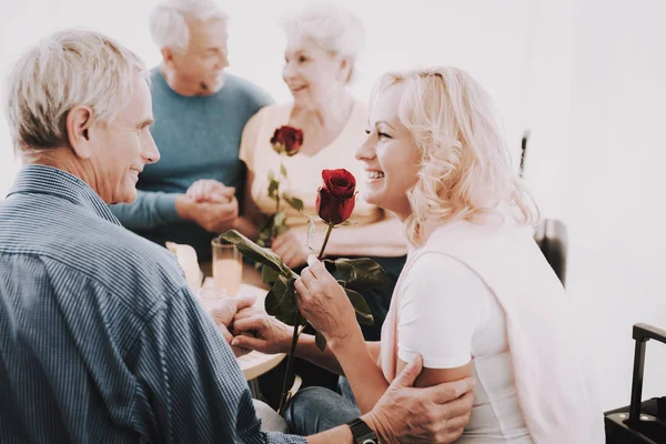 老人は待合室で女性にバラを与えます 手に赤いバラ 空港で上級者は 観光概念 航海の老夫婦 年金受給者のための休暇 荷物を持つ人々 休暇の旅行者 — ストック写真
