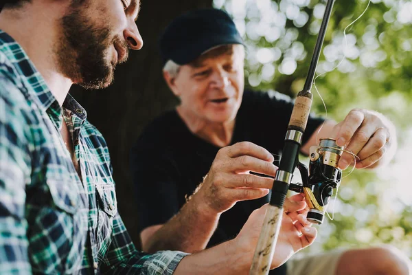 Old Father with Bearded Son Fishing on River in Summer. Relaxing Outdoor. Bearded Young Man. Men near Lake. Fishing Rod in Hands. Sports in Summer. Weekend on River. Adult Fishermen.