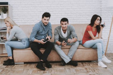 Evde parti üzerinde video oyunları oynarken gençler. Abur cubur yeme. Kapalı eğlenceli. Genç kız. Genç bir adam. Koltukta oturuyor. Arkadaş grubu parti. Kapalı faaliyetleri kavramı. Konsol oyun kavramı.