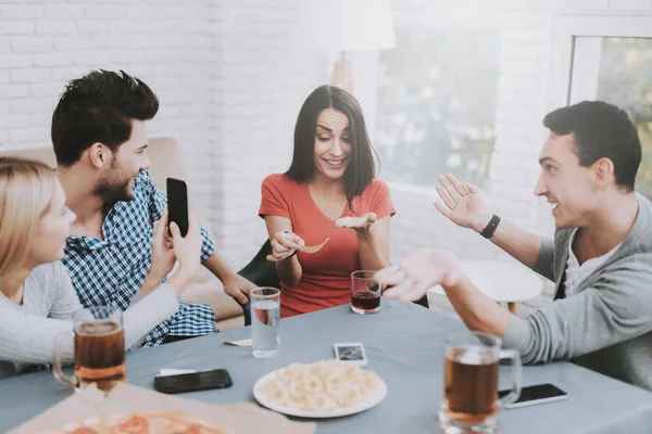 Young Smiling People Have Fun on Party at Home. Playing Games. Eating Snacks. Indoor Fun. Young Smiling Girl. Young Smiling Guy. Sitting at Table. Party with Friends. Indoor Activities Concept.