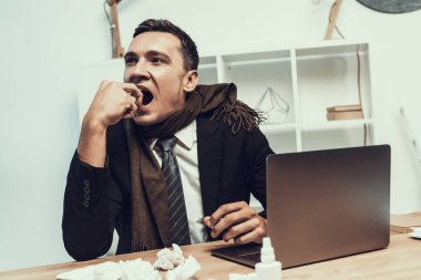 Hasta adam ofiste oturan eşarp ile takım elbiseli. Modern Ofis Yöneticisi. Sağlık kavramı. Modern ofis. Hasta işçi. Office sağlık hizmeti. Ahşap masa. Dijital aygıt. Resepsiyon üstünde Laptop.