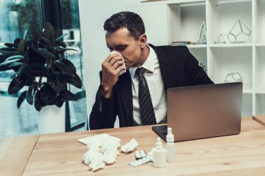 Hasta adam ofiste oturan eşarp ile takım elbiseli. Modern Ofis Yöneticisi. Sağlık kavramı. Modern ofis. Hasta işçi. Office sağlık hizmeti. Ahşap masa. Dijital aygıt. Resepsiyon üstünde Laptop.