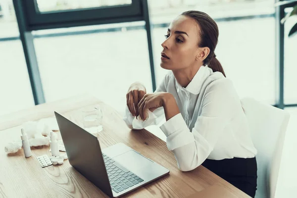 Young Sick Woman in White Shirt Sitting in Office.Healthcare Concept. Modern Office. Sick Worker. Healthcare in Office. Wooden Table. Digital Device. Laptop on Desk. Young Woman in Office.