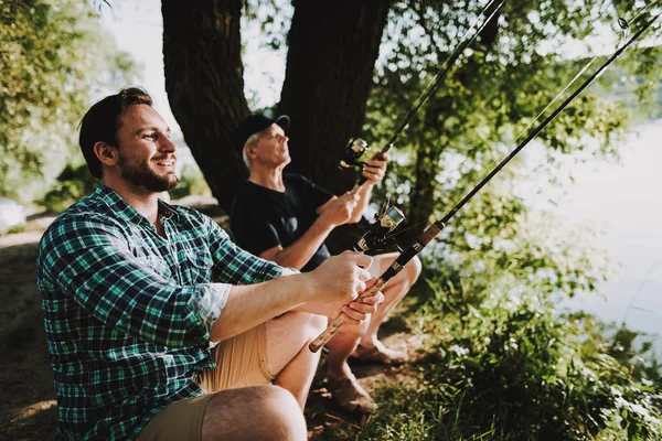 Young Man with Son and Father Fishing on River in Summer. Relaxing Outdoor. Old Man and Boy. Men near Lake. Fishing Rod in Hands. Sports in Summer. Weekend on River. Aged Fisherman.