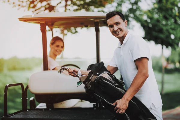 愉快的年轻夫妇在白色购物车在高尔夫球场上 年轻的家庭 高尔夫俱乐部 夏天的运动 在野外的车辆 户外乐趣在夏天 司机与汽车 健康的生活方式概念 假期中的情侣 — 图库照片