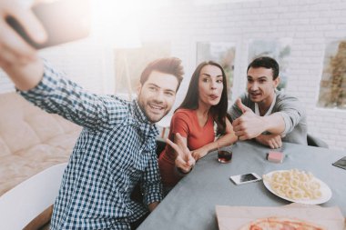 Genç gülümseyen insanlar alarak resmi parti için evde. Adam akıllı telefon. Kapalı eğlenceli. Genç gülümseyen kız. Genç gülümseyen adam. Masada oturuyor. Arkadaş grubu parti. Kapalı faaliyetleri kavramı.