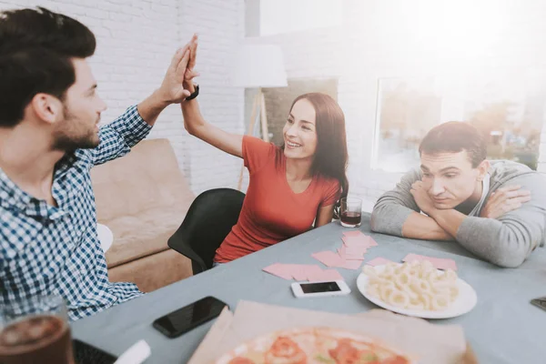 Young Smiling People Have Fun on Party at Home. Playing Games. Eating Snacks. Indoor Fun. Young Smiling Girl. Young Smiling Guy. Sitting at Table. Party with Friends. Indoor Activities Concept.