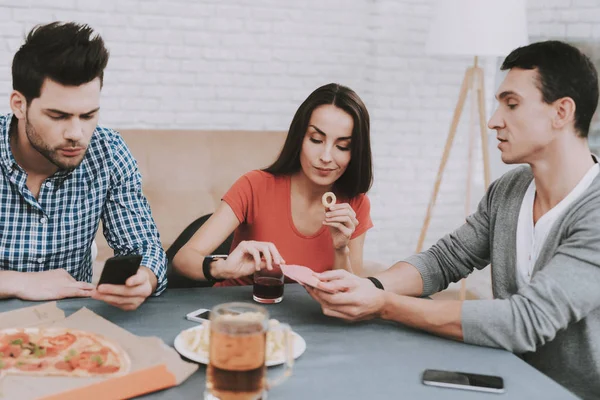 Young Smiling People Have Fun on Party at Home. Playing Games. Eating Snacks. Indoor Fun. Young Smiling Girl. Young Smiling Guy. Sitting at Table. Party with Friends. Indoor Activities Concept.