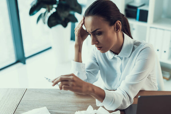 Молодая больная женщина в белой рубашке сидит в офисе. Концепция здравоохранения. Современный офис. Больной работник. Здравоохранение в офисе. Деревянный стол. Цифровое устройство. Ноутбук на столе. Молодая женщина в офисе
.