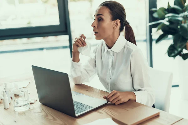 Young Sick Woman in White Shirt Sitting in Office.Healthcare Concept. Modern Office. Sick Worker. Healthcare in Office. Wooden Table. Digital Device. Laptop on Desk. Young Woman in Office.