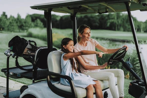 Young Mother and Daughter with Cart on Field. Happy Family. Little Girl. Driver with Car. Healthy Lifestyle Concept. Golf Club. Sports in Summer. Vehicle on Field. Outdoor Fun in Summer.