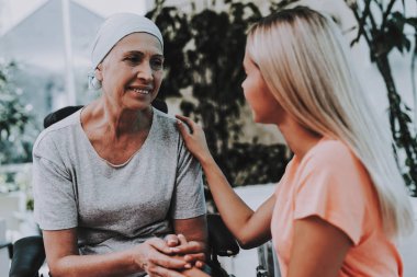 Hastanın rehabilitasyon uğrar. Kanser için tedavi sonrası. Kanser hastası bir tekerlekli sandalye üzerinde. Kızı olan bir kadın. Kadın memnun bkz: kızı. Kadın kurtarma. Remisyon. Kliniği. Kanser hastası.