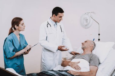Yaşlı adam hastanede yatıyor. Klinik hasta adam. Doktor ve hasta. Genç doktor hasta ile. Doktor ile hemşire bakımı. İnsanlar tıbbi koğuşta. Doktor ile hasta ve hemşire. Doktor stetoskop ile.