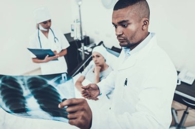 Doktor ve hemşire koğuşta. Kadın rehabilitasyon uğrar. Kanser için tedavi sonrası. Hemşire notları. Ranza kadınlarda. Doktor röntgen görünüyor. Doktor kliniğinde. Kanser hastası. Kadının kafasına eşarp.