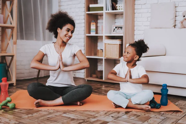 Mother with Young Girl Training. Smile Girl and Young Mother Sport for all Family. Yoga for Family. Mother and Daughter Together. Good Day for Family. Studio and Happy Time Together. Mulatto and Girl.