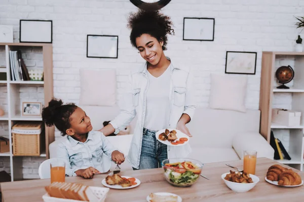 Young Girl and Mother Eat Foor. Happy Day For Little Girl. Mulatto Girl and Happy Mother Time Together. Child and Happy Mother. Siting Time. Creative Time with Family. Smile for Girl. Beautiful Time.