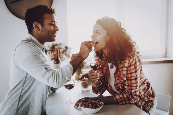 Boyfriend Is Feeding Girlfriend With Strawberry. Weekend Concept. Chilling At Kitchen. Holiday Resting. Smiling Together. Having Fun. Romantic Date. Afro American Couple Drinking Wine.