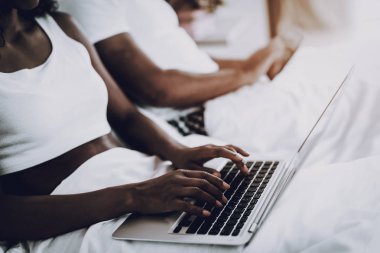 Afro Amerikan çift yatakta laptop.